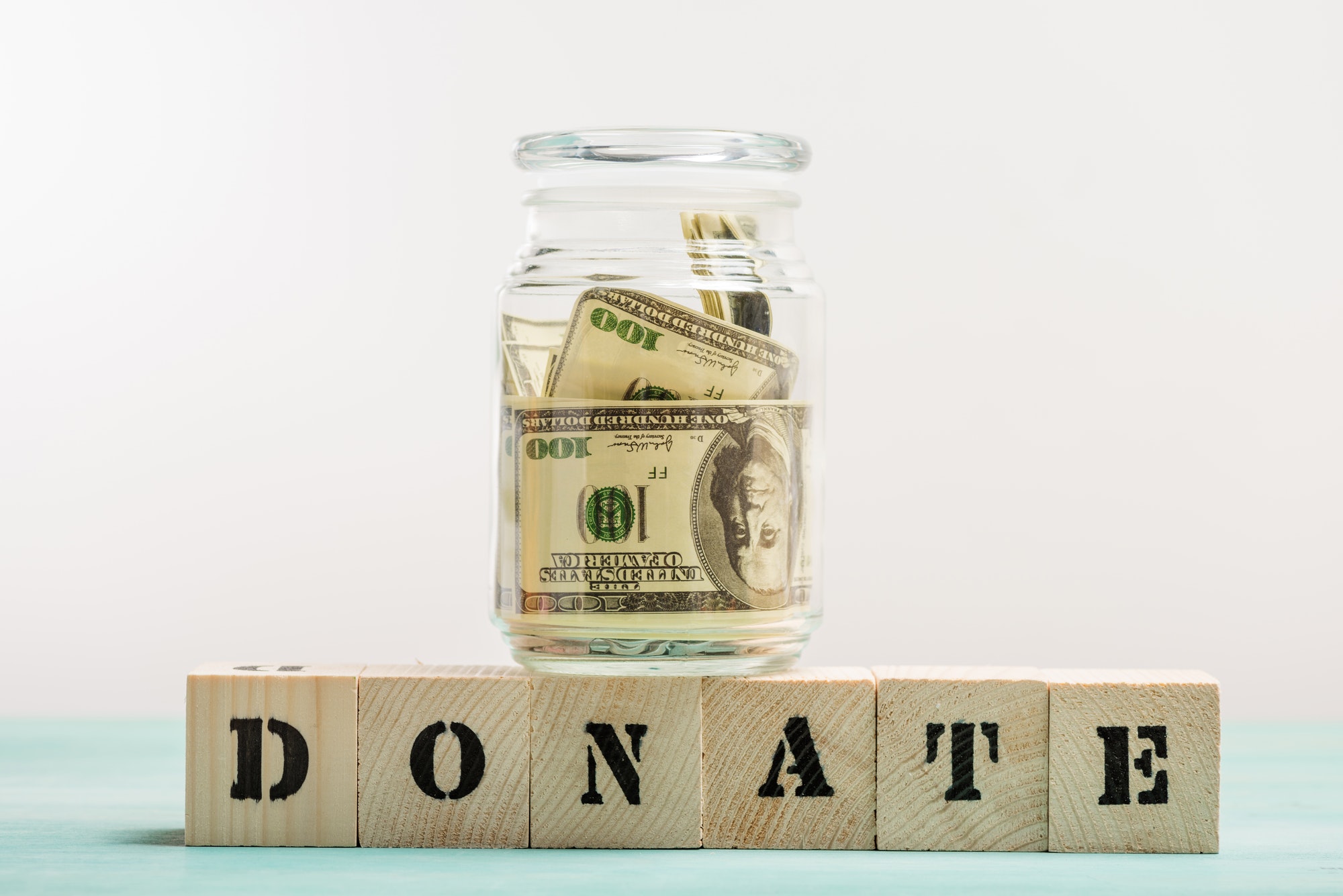 Dollar banknotes in glass jar and wooden cubes with donate lettering, donation concept